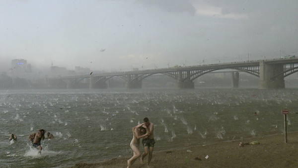 In this photo taken on a smartphone on Saturday, July 12, 2014, people run to shelter from hailstorm on the beach at Ob River, the major river in western Siberia in Novosibirsk, Russia. The Investigative Committee said in a statement published online Mond