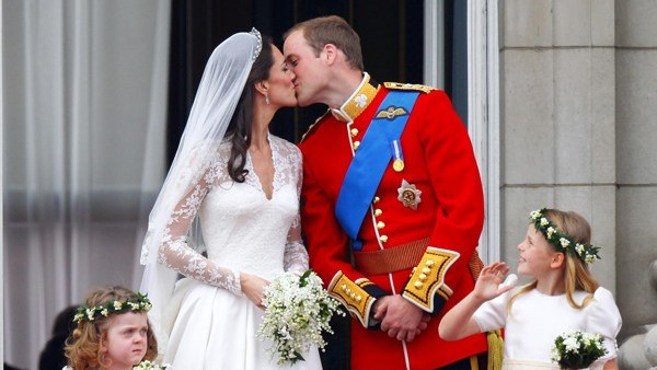 Prince William and his wife Kate Middleton, who has been given the title of The Duchess of Cambridge, kiss on the balcony of Buckingham Palace, London watched by bridesmaids Margarita Armstrong-Jones (right) and Grace Van Cutsem (left), following their we