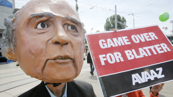 A protester wearing a mask depicting FIFA President Sepp Blatter stands in front of the building where the 65th FIFA congress takes place in Zurich, Switzerland, Friday, May 29, 2015. Protesters from the global campaign movement Avaaz demand the resignati
