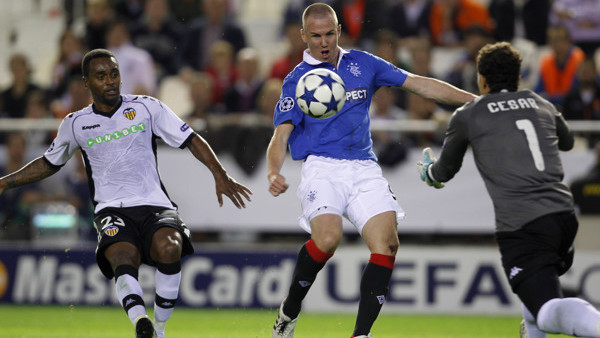 Rangers player, Kenny Miller from Scotland, center, duels for the ball with Valencia goalkeeper Cesar Sanchez from Spain, right, and Luis Miguel Brito from Portugal, left, during their Group C Champions League soccer match at the Mestalla Stadium in Valen